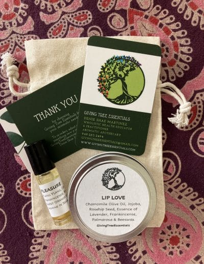 Small pouch with a thank you note, lip balm tin, libido support essential oil roll, and business cards on a purple patterned cloth.