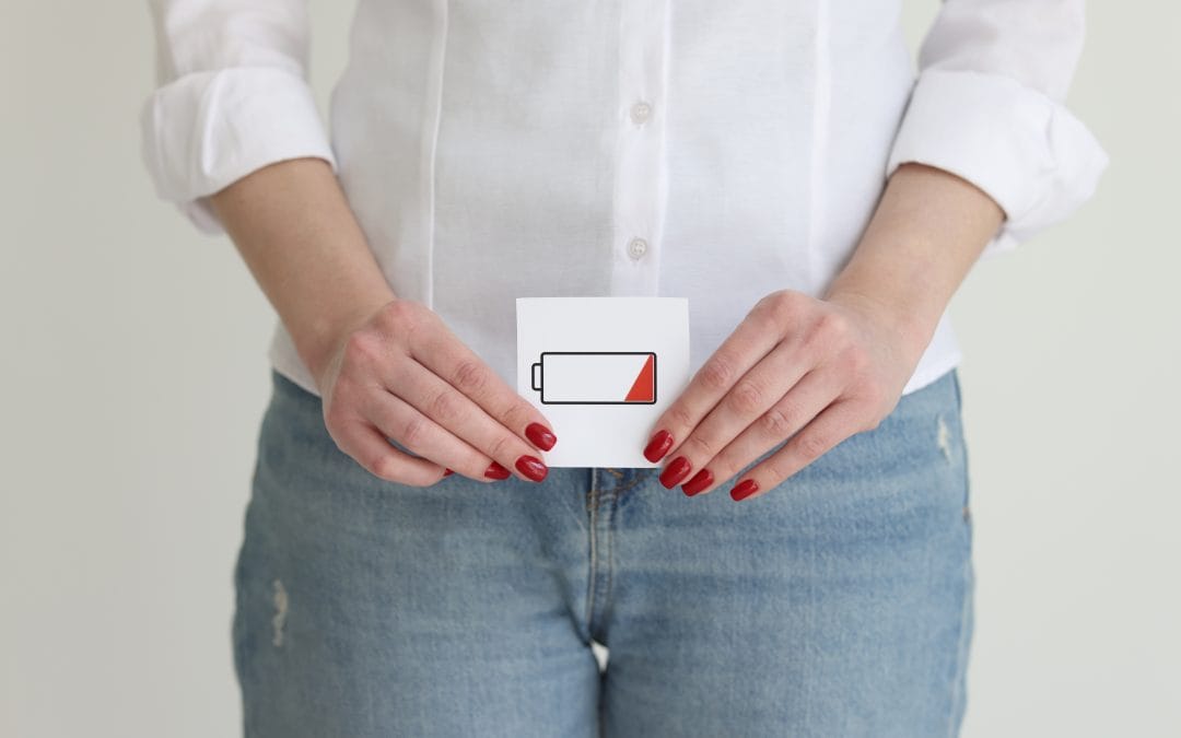 Low on Libido Acupuncture Person holding a low battery sign, wearing a white shirt and jeans.